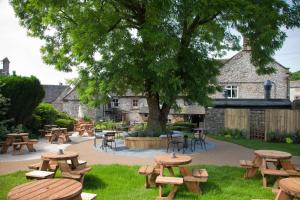 un groupe de tables de pique-nique et de chaises sous un arbre dans l'établissement Devonshire Arms, à Hartington