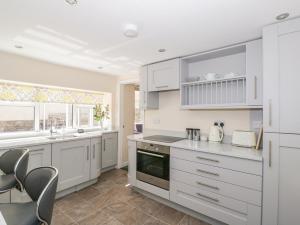 a kitchen with white cabinets and a counter top at Rose Cottage in Lydney