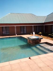 a swimming pool with a fountain in front of a house at Royal Olympia Lodges and Safaris Livingstone in Livingstone