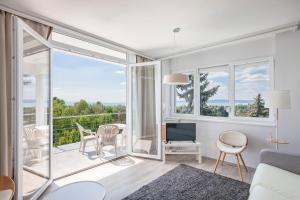 a living room with white furniture and a large window at Mirador Balaton Panorama Villa & Jacuzzi in Balatonakarattya