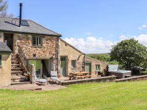 a stone house with a patio and a table at Sunbury Barn in St. Agnes