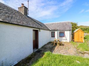 una casa de campo blanca con una mesa de picnic frente a ella en 2 Tougal, en Mallaig