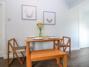 a wooden table with two chairs and a vase of flowers at 2 Tougal in Mallaig