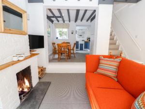an orange couch in a living room with a fireplace at Minnow Cottage in Malpas