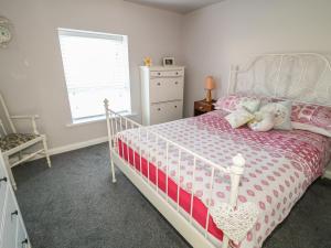 a bedroom with a pink and white bed with stuffed animals on it at Cranny Corner in Ballymena