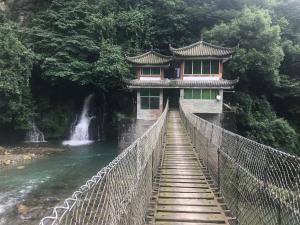 un puente sobre una cascada con un edificio en él en Mount Emei Feng Lin Yue Hotel, en Emeishan