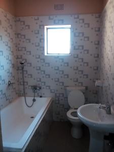 łazienka z wanną, toaletą i umywalką w obiekcie Royal Olympia Lodges and Safaris Livingstone w mieście Livingstone