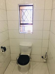 a bathroom with a toilet with a black seat and a window at Riverton Manor in Centurion