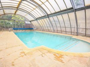 een groot zwembad in een gebouw met een plafond bij Stone Wheel Cottage in Hook Norton