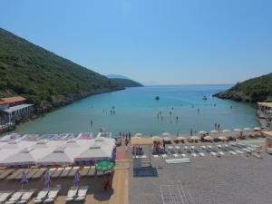 a beach with umbrellas and people in the water at Trsteno Beach Apartments in Budva