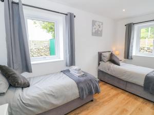 Dos camas en una habitación con dos ventanas. en Llwyd Coed Canol, en Caernarfon