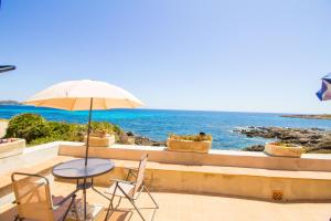 a table and chairs with an umbrella and the ocean at Authentic fisherman's house on the seafront in Cala Ratjada
