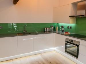 una cucina con armadi bianchi e pareti verdi di Repton Engine Shed a Whitby