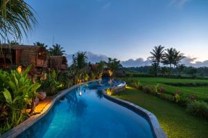 a swimming pool in a resort at night at Beehouse Dijiwa Ubud in Ubud