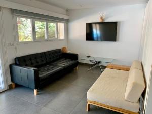 a living room with a black couch and a tv at Atlanticvilla in Hourtin