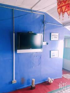 a blue wall with a tv in a room at Vamoose Quaint Wood Cottage in Darjeeling