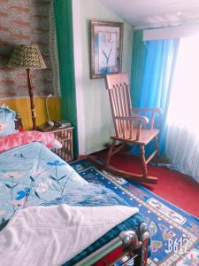 1 dormitorio con mecedora y 1 cama en Vamoose Quaint Wood Cottage, en Darjeeling 15 fotos más