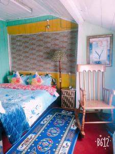 a bedroom with a bed and a chair and a table at Vamoose Quaint Wood Cottage in Darjeeling
