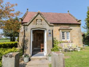 a small stone house with a door and chairs at Fenwick Retreat at Fenwick Lodge in Newcastle upon Tyne
