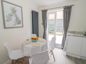 uma sala de jantar branca com uma mesa e cadeiras brancas em Midsummer Cottage em Stratford-upon-Avon