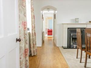 a living room with a fireplace and a table and chairs at Iona Cottage in Duns