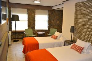 Habitación de hotel con 2 camas con sábanas de color naranja y blanco en Hotel ACA El Calafate en El Calafate