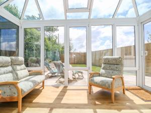 a conservatory with two chairs and a couch and windows at Strawberries & Cream Retreat in Redruth