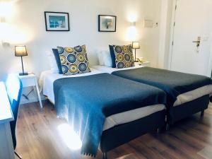um quarto com 2 camas com cobertores e almofadas azuis em Hotel Botanico de Coimbra em Coimbra