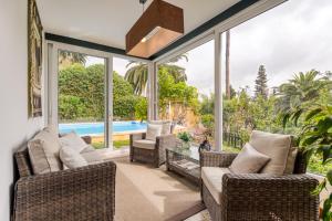 a screened in porch with wicker furniture and glass windows at LAS HORTENSIAS WITH PRIVATE POOL in Santa Brígida