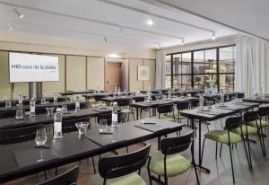 a conference room with tables and chairs and a screen at H10 Casa de la Plata in Seville