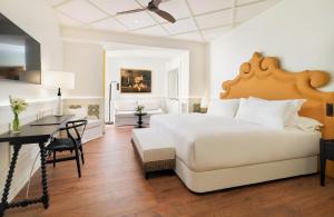 a white bedroom with a large bed and a desk at H10 Casa de la Plata in Seville +70 photos