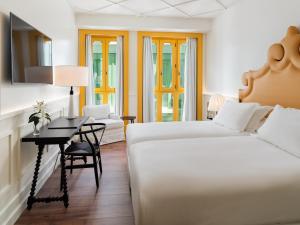 a hotel room with two beds and a desk with a desk at H10 Casa de la Plata in Seville