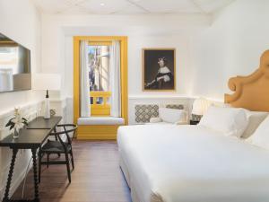 a bedroom with a large white bed and a desk at H10 Casa de la Plata in Seville