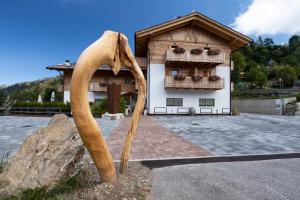 a statue of a large wooden weapon in front of a building at Garnì & Wellness Anderle in Vignola
