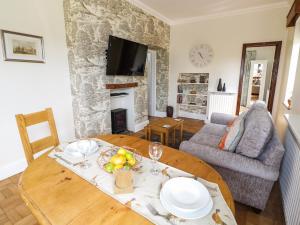a living room with a wooden table and a fireplace at Fox Cottage in Droitwich