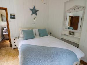 een slaapkamer met een groot wit bed met blauwe kussens bij Fox Cottage in Droitwich