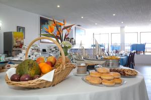 a table with baskets of fruit and pastries on it at Aparthotel Barracuda in Ponta Delgada