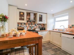 a kitchen with white cabinets and a wooden table at Meadow View Cottage in Exmouth