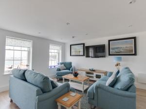 a living room with two blue chairs and a table at 5 The Beaches in Weymouth