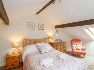 a bedroom with a bed and a red chair at Woodstock Cottage in Axminster