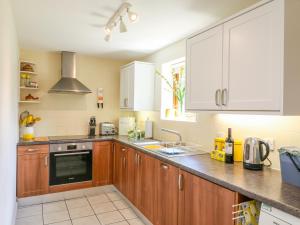 a kitchen with wooden cabinets and a stove top oven at Woodstock Cottage in Axminster