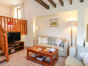 a living room with a couch and a tv at Woodstock Cottage in Axminster