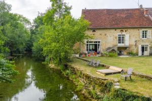 a stone house next to a river with chairs at Côté Rivière in Nevy-sur-Seille