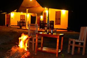 a table and chairs sitting next to a fire at Ceylon Safari Cottage in Udawalawe
