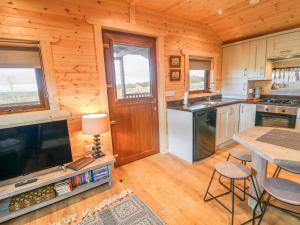 eine Küche mit einem Tisch und einem TV in einer Hütte in der Unterkunft Alken Cabin in Bushmills