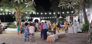 Une foule de gens debout dans une cour la nuit dans l'établissement Masseria Don Sante, à Fasano