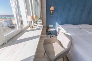 um quarto com uma cama, uma cadeira e janelas em Dvina Hotel em Arcangel