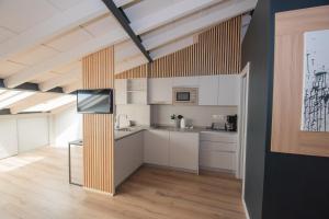 a kitchen with white cabinets and a flat screen tv at Apartamentos Puerta de Llanes in Llanes