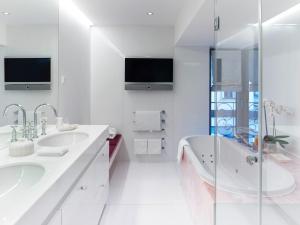 a white bathroom with two sinks and a tub at Thurnher's Alpenhof in Z&uuml;rs am Arlberg
