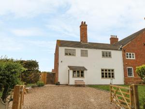 a white house with a bench in front of it at Warren House Cottage in Market Rasen